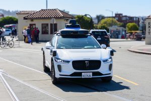 Waymo One Jaguar driverless autonomous car equipped with lidar sensors and cameras drives on a road.